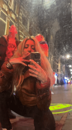 Woman takes street selfie amid projected lights in Amsterdam