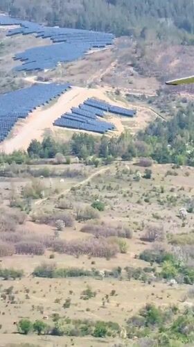 Small aircraft flies over solar farm in Bulgarian countryside