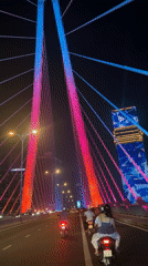 Motorbike passenger crosses colorful lit bridge in Ho Chi Minh City