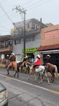 Horseback riders in cowboy hats ride through Altotonga streets