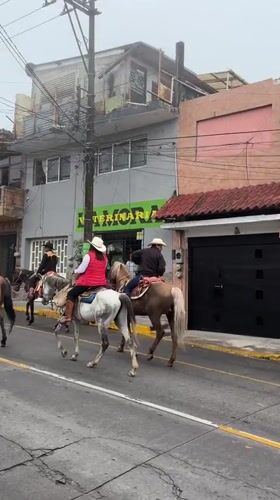 Horseback riders in cowboy hats ride through Altotonga streets