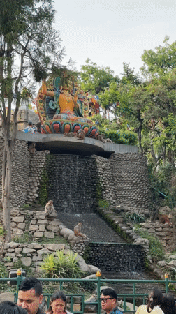 Monkeys gather around waterfall statue in Kathmandu