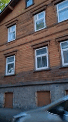 Vehicle passes wooden building in Tallinn evening drive