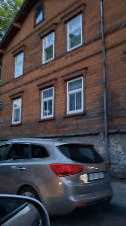 Vehicle passes wooden building in Tallinn evening drive