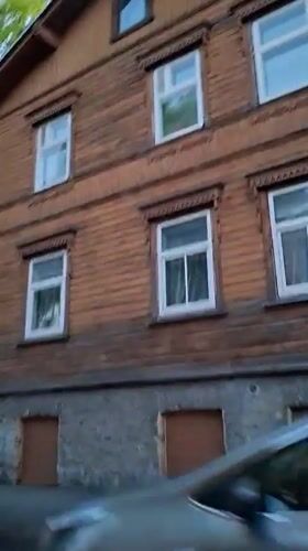Vehicle passes wooden building in Tallinn evening drive