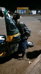 Nighttime auto-rickshaw breakdown and repairs on a wet Bukuru road
