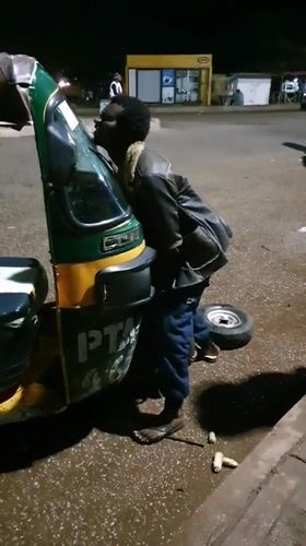 Nighttime auto-rickshaw breakdown and repairs on a wet Bukuru road