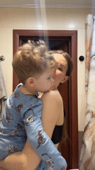 Woman holds child in bathroom during early morning hours