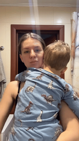 Woman holds child in bathroom during early morning hours