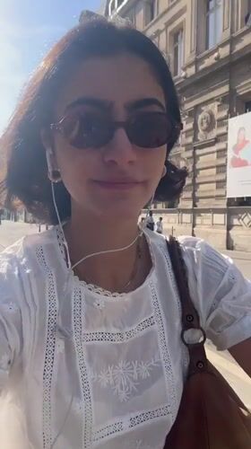 Woman rides scooter through Paris streets wearing headphones