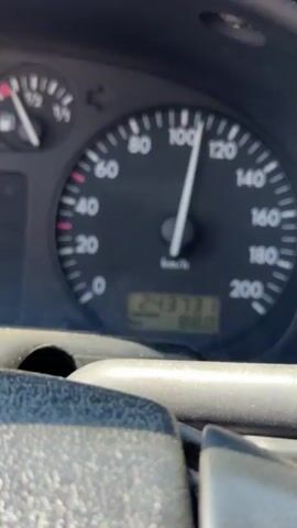 The video captures a view from inside a car, focusing on the dashboard and the road ahead. The speedometer shows a speed of approximately 100 km/h, with the odometer reading 243731 km. The fuel gauge indicates the tank is just over half full. The road ahead is visible through the windshield, with other vehicles in the distance. The overall impression is of a car traveling at a moderate speed on a clear, sunny day.
