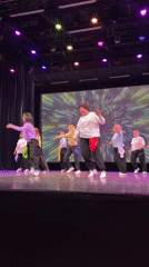 Dance group performs coordinated routine on stage