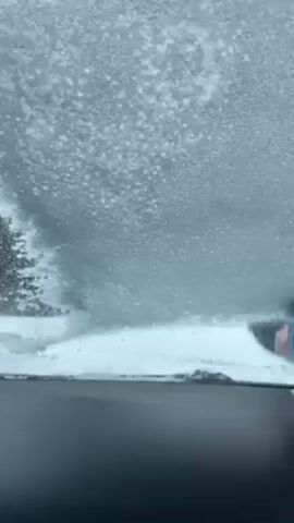 Here’s the detailed description of the video:
The video shows a person scraping ice off of a car windshield from the inside. The windshield is heavily covered in ice. As the ice is scraped away, a sign outside the car becomes visible, showing what appears to be a pet store or animal service. The environment shows a snowy scene, with trees and telephone poles visible in the background.