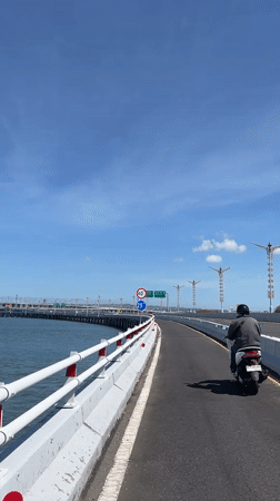 Riding Bali's coastal toll bridge with GWK in the backdrop