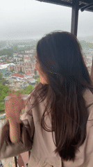 Woman poses playfully on Sochi balcony during rainy afternoon