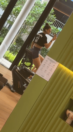 Woman multitasks with phone during gym workout in Thailand