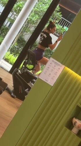 Woman multitasks with phone during gym workout in Thailand
