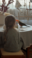 Girl in pajamas shares table moment with colorful parrot