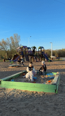 Children play at sunny Tobolsk playground as woman takes selfies