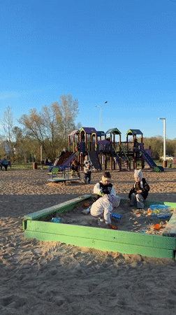Children play at sunny Tobolsk playground as woman takes selfies