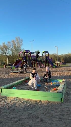 Children play at sunny Tobolsk playground as woman takes selfies