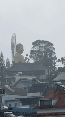 Golden Buddha statue towers over fog-covered Đà Lạt cityscape