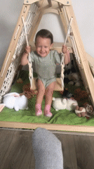 Baby plays in backyard swing in Wisła, Poland