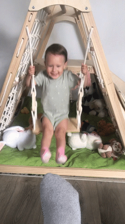 Baby plays in backyard swing in Wisła, Poland