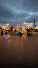 Street band plays cobblestone plaza at dusk to a growing crowd