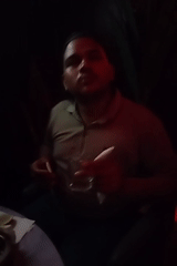 Man sits with drink at dimly lit venue in Dhaka
