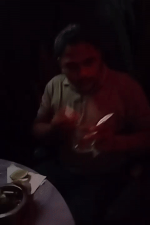 Man sits with drink at dimly lit venue in Dhaka