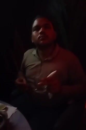 Man sits with drink at dimly lit venue in Dhaka