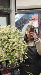 Woman takes flower shop selfie with daisy bouquet in Latvia