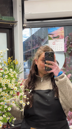 Woman takes flower shop selfie with daisy bouquet in Latvia
