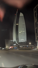 Illuminated skyscraper anchors a quiet city street at night