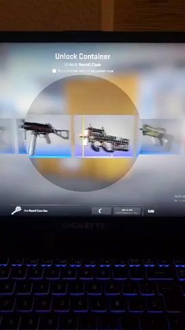 A person is opening a Recoil Case in the game Counter-Strike: Global Offensive on a Gigabyte laptop. The laptop's keyboard features a blue backlight. The case opening reveals a FAMAS | Meow 36 skin.