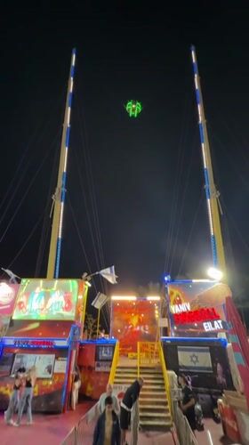 Night fairground slingshot ride operates in Eilat, Israel