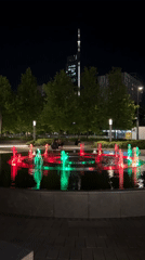 Evening crowds gather around illuminated fountain in Warsaw