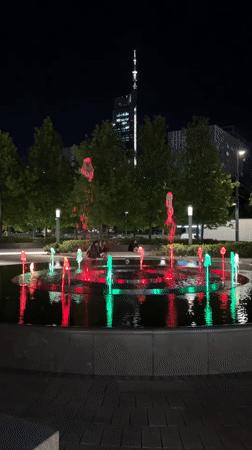 Evening crowds gather around illuminated fountain in Warsaw