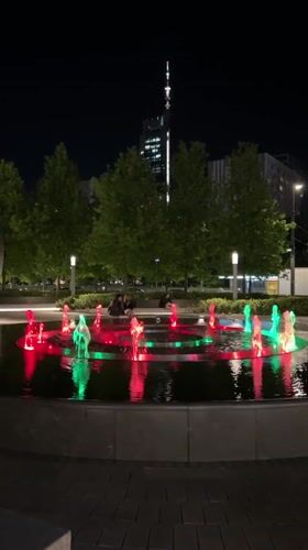 Evening crowds gather around illuminated fountain in Warsaw