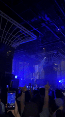 Concert performer takes stage under blue lights in Hong Kong