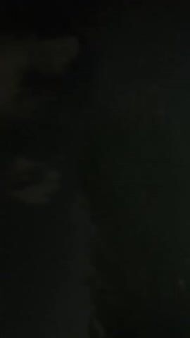 The video shows a dark, cloudy sky at night. There are pockets of light in the clouds, suggesting artificial lighting or moonlight filtering through. The lower portion of the video shows dark shapes that could be trees or buildings, but they are not clearly discernible.