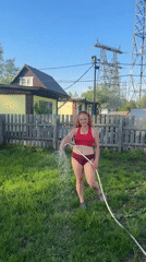 Woman and boxer dog play with garden hose in Chaikovsky backyard