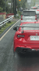 Sports car and minivan stopped on wet road in Indonesia