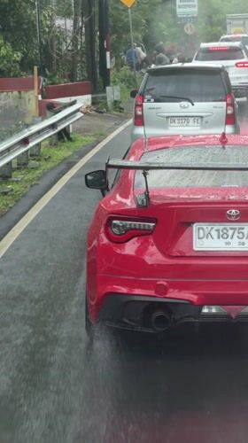 Sports car and minivan stopped on wet road in Indonesia