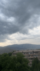 Cloudy skies over a valley town with apartment buildings and greenery