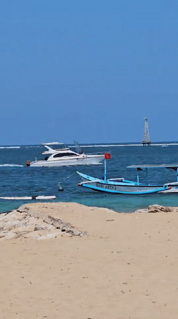 Colorful outrigger boats rest on a calm Bali beach