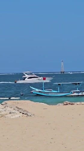 Colorful outrigger boats rest on a calm Bali beach
