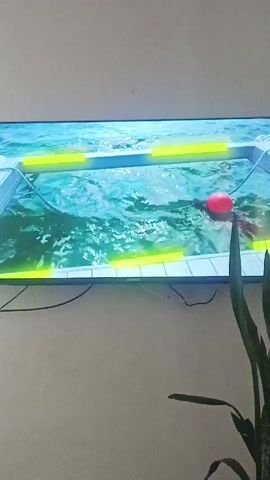 The TV screen shows a pool surrounded by a yellow-lighted platform. A young person wearing a green leafy shirt and red shorts enters the scene, walks to a white shelf, and picks up a pair of binoculars.
