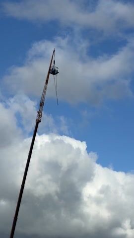 The video shows a bungee jump taking place from a platform atop a very tall crane. A person jumps from the platform, and the bungee cord stretches as they fall. The background is a blue sky with scattered clouds. A child's voice can be heard in the audio.